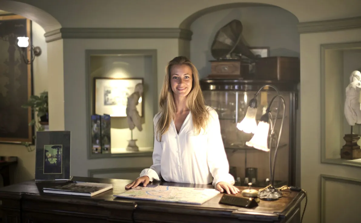Smiling hotel front desk receptionist standing at the reception desk
